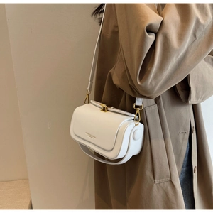 Detail view of white leather crossbody bag showing golden lock and elegant fashion text