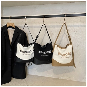 Trois grands sacs cabas en toile de couleurs variées suspendus sur un portant moderne