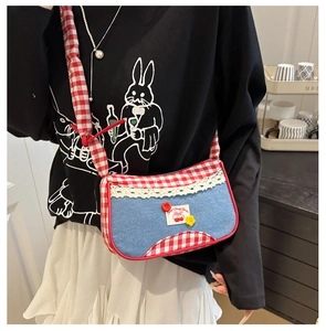 Detail of blue denim crossbody bag with red checkered pattern and cherry embroidery