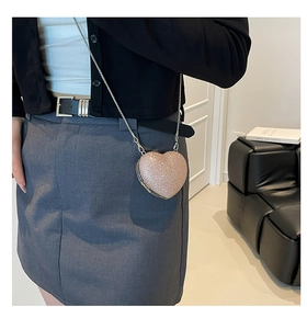 Model wearing a pink glitter heart crossbody bag with a silver chain strap for party