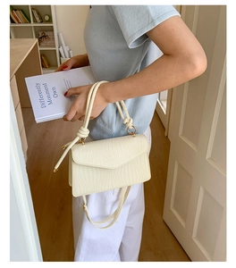 Petit sac carré tissé crème avec détails texturés tenu à la main