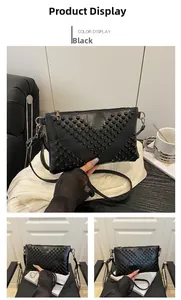 Detail of a black envelope clutch with V-shaped rivet studs and silver hardware zipper