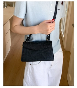 Vue détaillée d'un sac à bandoulière tissé noir minimaliste porté par un mannequin