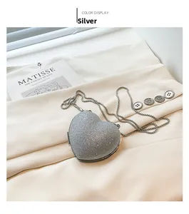 Close-up of heart-shaped silver sequin crossbody bag with chain on Matisse art background