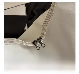 Detail of smooth double metal zippers on white faux leather tote bag with pebble texture