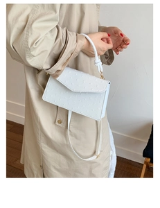 Sac à main carré rétro blanc avec texture gaufrée porté par un mannequin en trench-coat