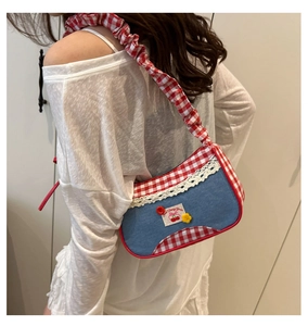 Detail of Y2K denim baguette bag with cherry patch, lace trim and gingham strap