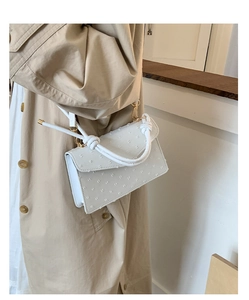 Vue détaillée d'un sac à main blanc vintage avec une poignée nouée unique et un fini texturé