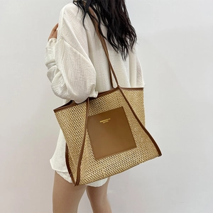 Large woven tote bag with brown leather trim and shoulder straps shown on model