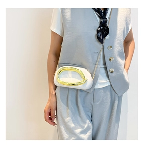 White acrylic evening clutch with gold ring hardware and chain strap on a model