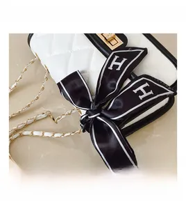 Close-up of quilted white leather bag with gold chain strap and H-print silk bow detail