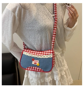 Detail of cute cherry label and lace trim on a red checkered crossbody bag