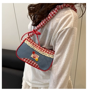 Detail of blue denim shoulder bag with red gingham trim and cherry embroidery