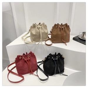 Detail view of four retro drawstring bucket bags in beige, brown, burgundy, and black leather