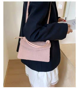 Close-up of a pink textured fabric crossbody bag worn by a model in a navy blazer
