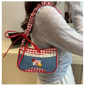 Detail of denim and red gingham shoulder bag with cherry embroidery and lace trim