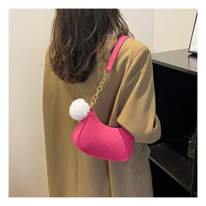 Stylish magenta crossbody bag with white pom-pom charm and gold chain strap detail