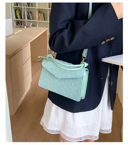 Détail du sac bandoulière bleu clair texturé doté d'une poignée nouée très originale