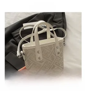 Close-up of white jacquard tote bag with geometric patterns and silver rivets