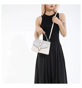 Détail du sac en cuir blanc avec rabat à paillettes argentées et fermoir en U doré