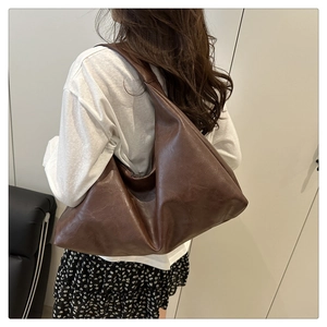 Detailed side view of a large brown faux leather hobo bag with a soft crescent shape