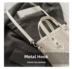 Detail of silver hardware hooks and jacquard texture on stylish crossbody bag