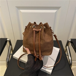 Brown suede drawstring bucket bag with leather strap in a minimalist summer style