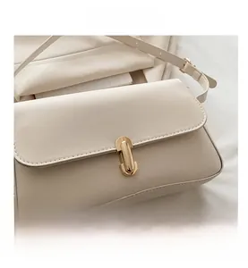 Detailed close-up of ivory shoulder bag featuring a polished gold U-shaped metal buckle