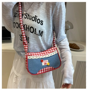 Close-up of denim shoulder bag with red gingham straps and cute cherry patch detail