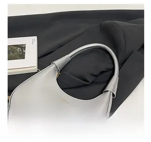 Detailed macro view of gray patent leather crescent bag with gold chain and brand logo