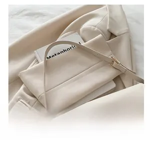 Detail showing the elegant beige shoulder bag with a polished gold metallic buckle closure