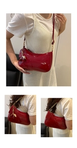 Detail of red patent leather shoulder bag with cherry charm and metal chain strap