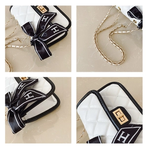 Detail of white quilted chain bag with gold twist lock and H-pattern silk scarf accent