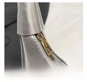 Close-up of premium gold-tone metal zipper on silver patent leather crescent bag