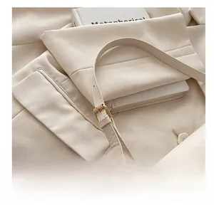 Close-up of adjustable golden pin buckle on minimalist cream leather shoulder bag strap