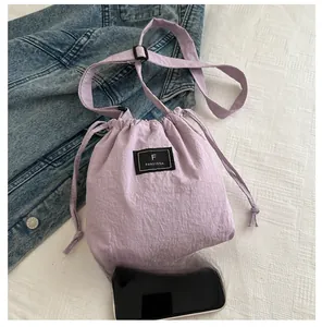Detail view of a lavender nylon drawstring bag showing size comparison with a smartphone