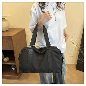 Detail view of large waterproof black oxford travel bag with sturdy handles and logo