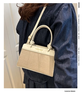 Detail of cream canvas handbag with leather handles worn over the shoulder by a model