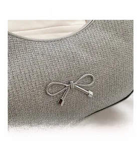 Macro detail of luxury silver crescent bag with textured fabric and metallic bow accent