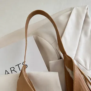 Detailed macro view of the brown leather shoulder strap on a stylish fringed tote bag.