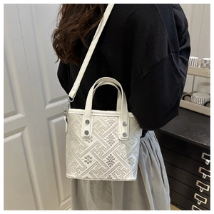 Detail of silver bucket bag with geometric flower texture and metallic rivets
