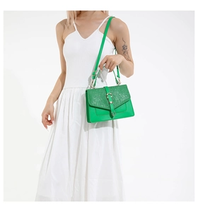Detail of green crossbody bag showing glitter sequins flap and golden metal buckle