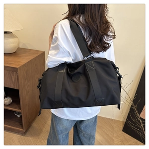 Detail of waterproof black travel bag with sturdy handles and adjustable shoulder strap