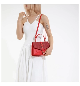 Détail d'un sac à main rouge à paillettes avec boucle dorée sur un mannequin