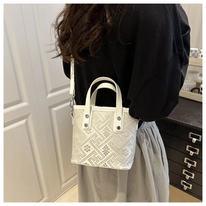 Detailed view of cream jacquard crossbody bag with geometric pattern and silver rivets