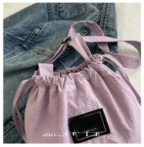 Detailed view of light purple drawstring bucket bag with pleated nylon fabric texture