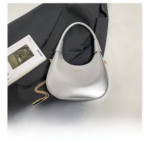 Detailed view of silver hobo bag with gold chain and smartphone for size reference