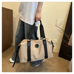 Detail of cross-stitched reinforced handles and fashion logo on beige nylon travel bag