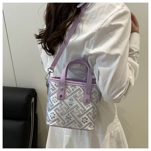 Close-up of purple jacquard mini bucket bag with geometric embroidery and silver rivets
