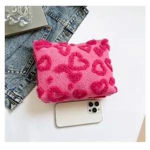 Detailweergave van de roze pluchen hartentas met smartphone als maatreferentie punt.